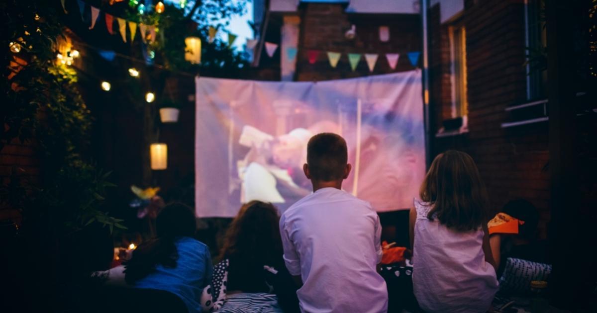 kids watching a movie on an outside projector