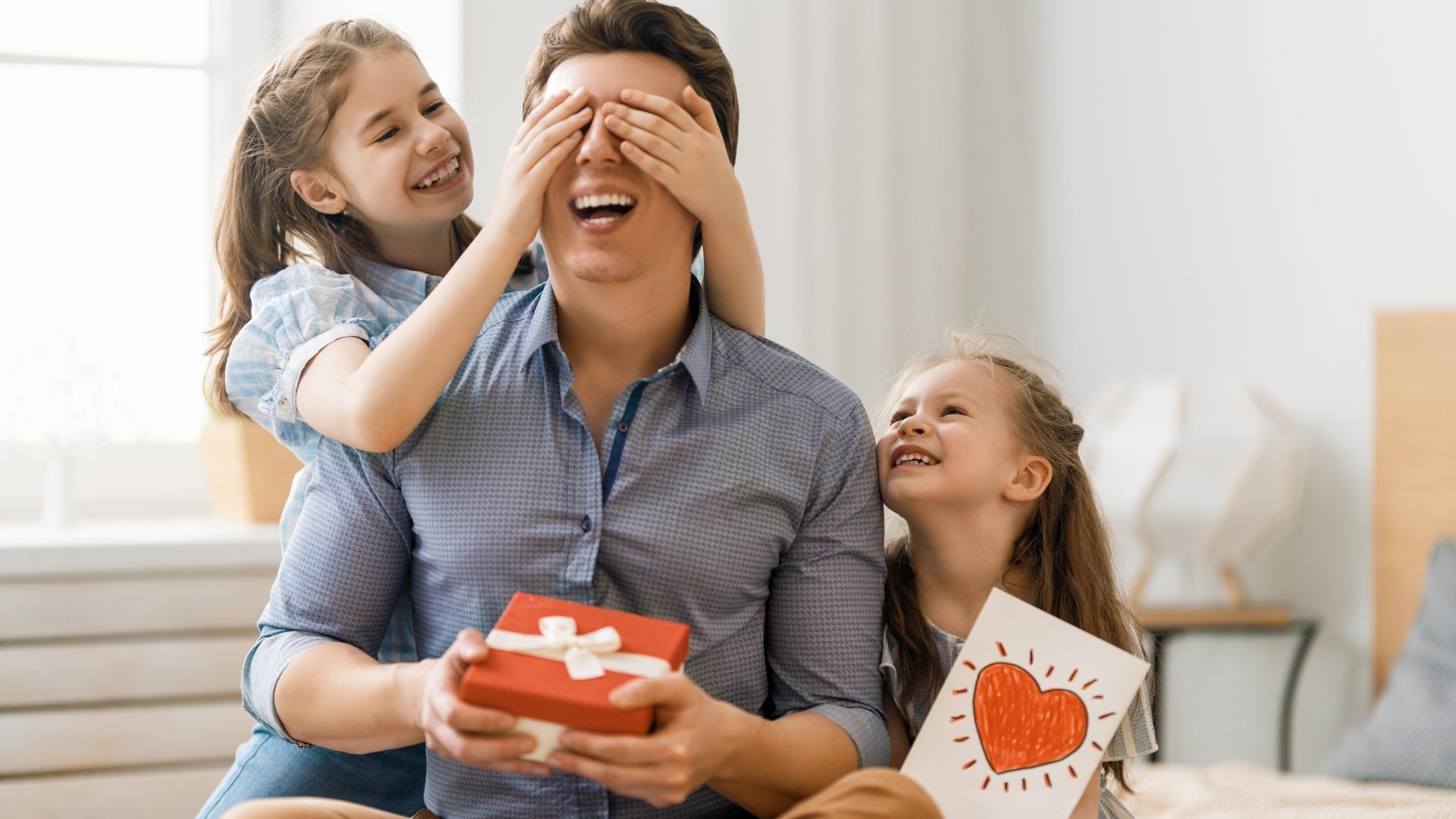 a father being surprised by his daughters with a gift and a card on father's day